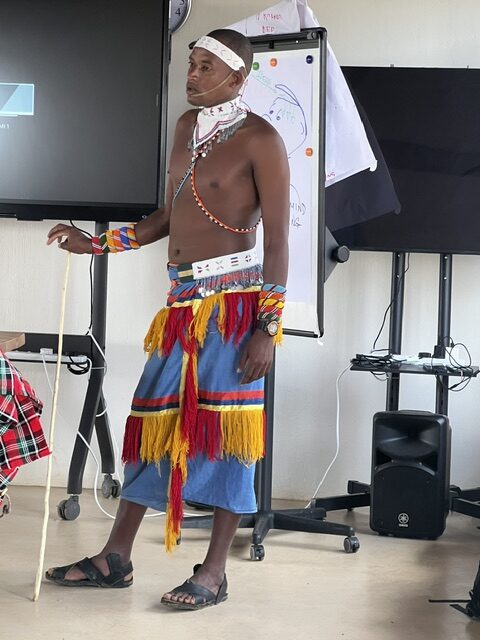 A Moran participant in traditional dress presents to the class beside a flip chart during the first Rangelands LAMP module.